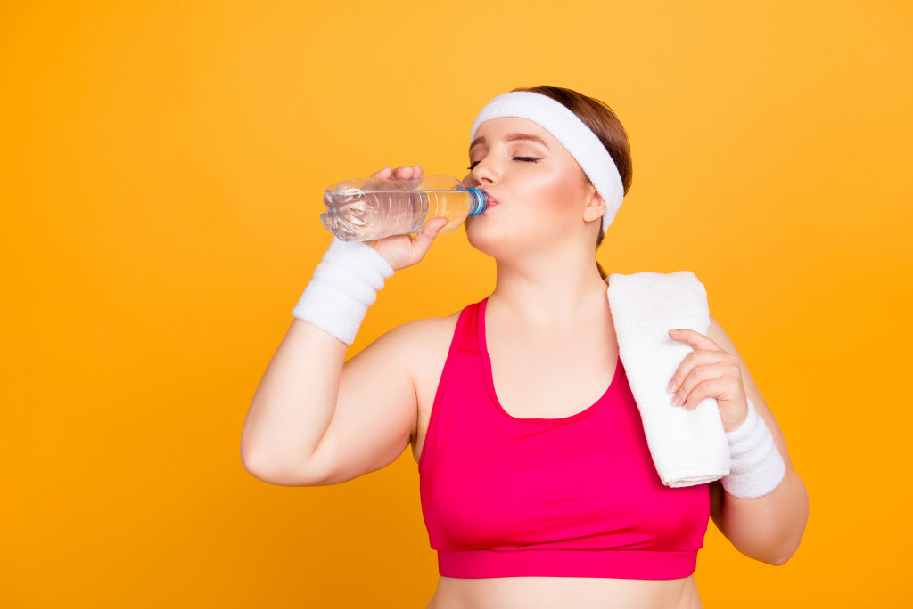 woman drinking water after exercising