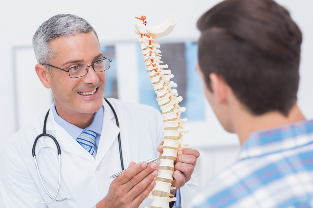 doctor smiling while showing his patient a scale of a spinal cord