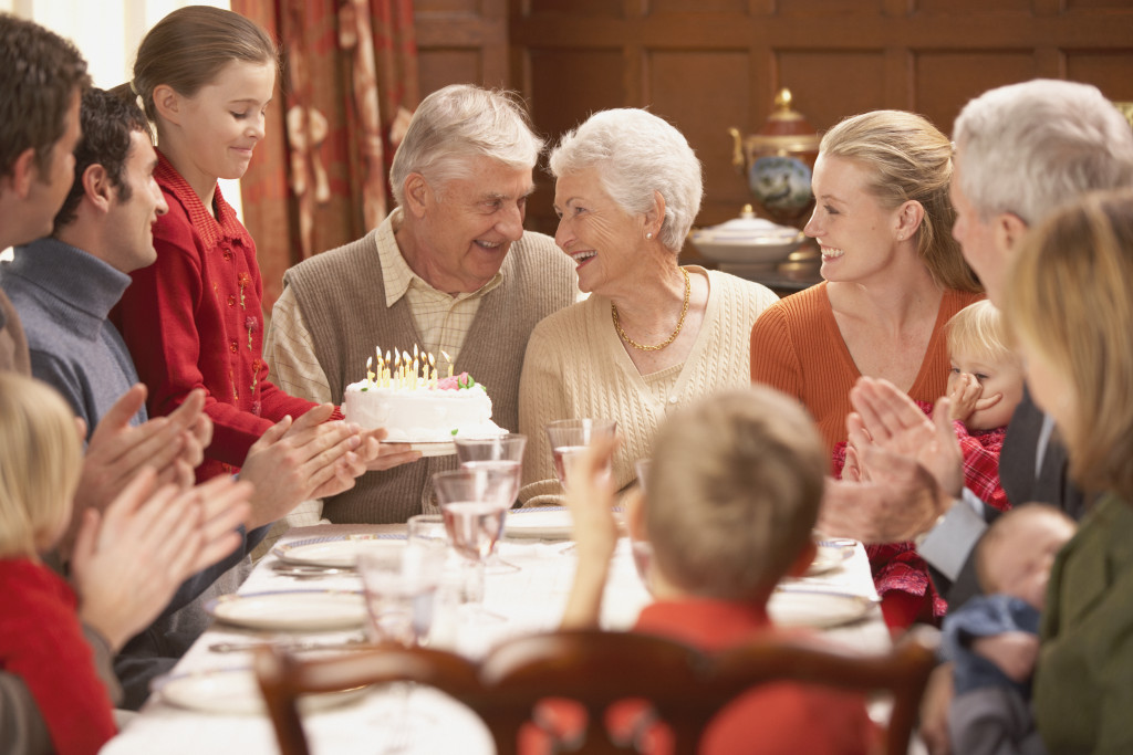 Grandmother with birthday cake and family at dinner table