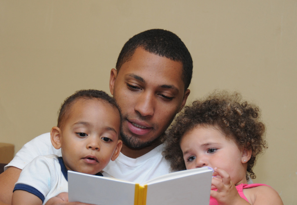 A father reading a book to his two kids