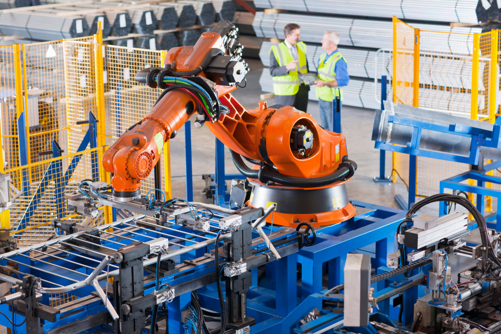 Robot used in a manufacturing plant with human employees in the background.