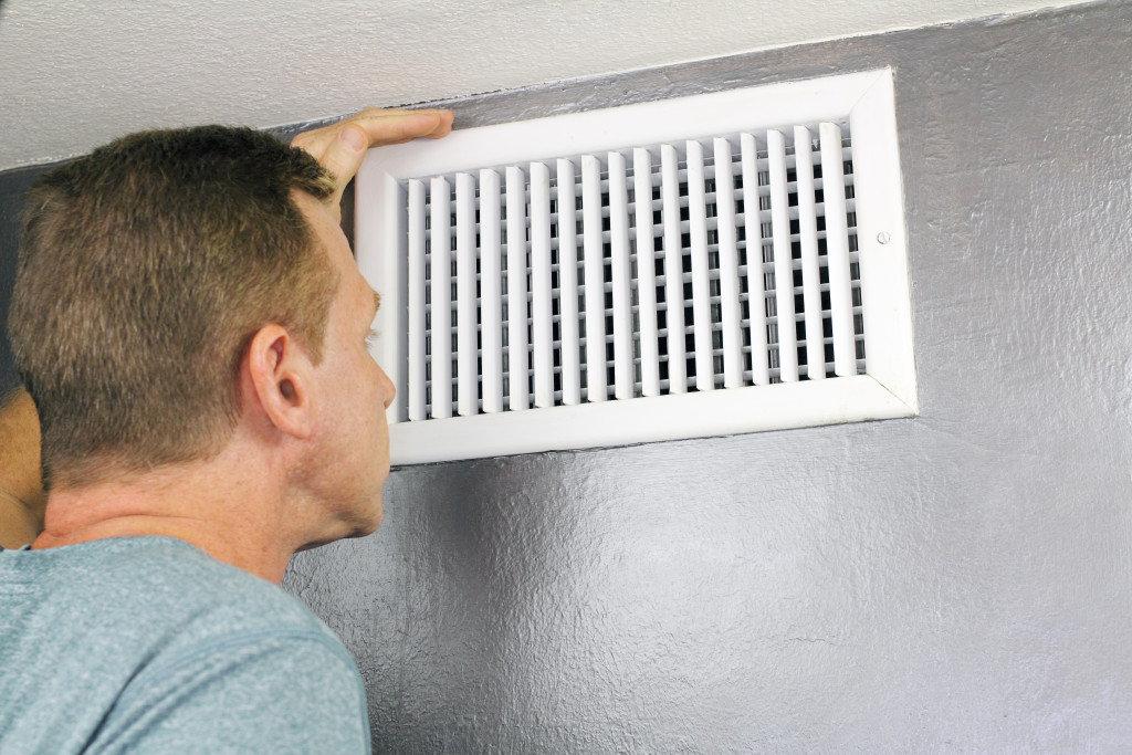 A man checking his air vent